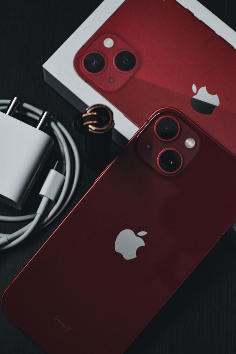 Red smartphone with accessories on dark surface, showcasing modern design.